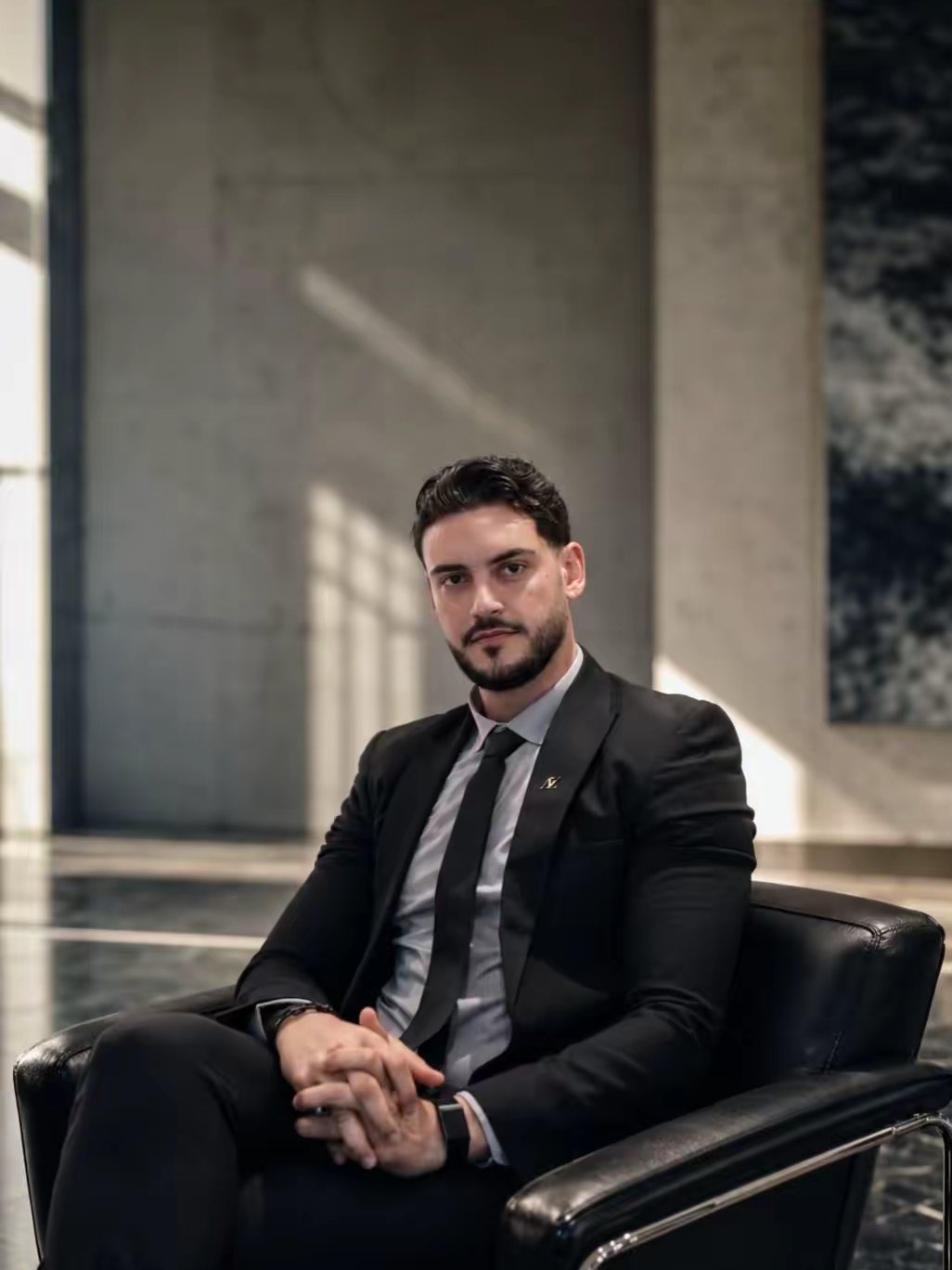 Mahmoud Ashri seated in a leather chair in a marble lobby, hands clasped